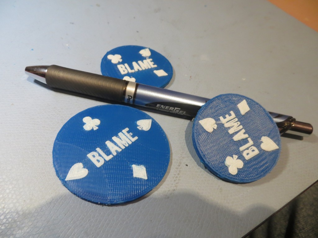3D printed version of the 'Duplicate Bridge Blame Chip'.  The chip laying on the pen is actually two chips glued together to form a 2-sided chip.